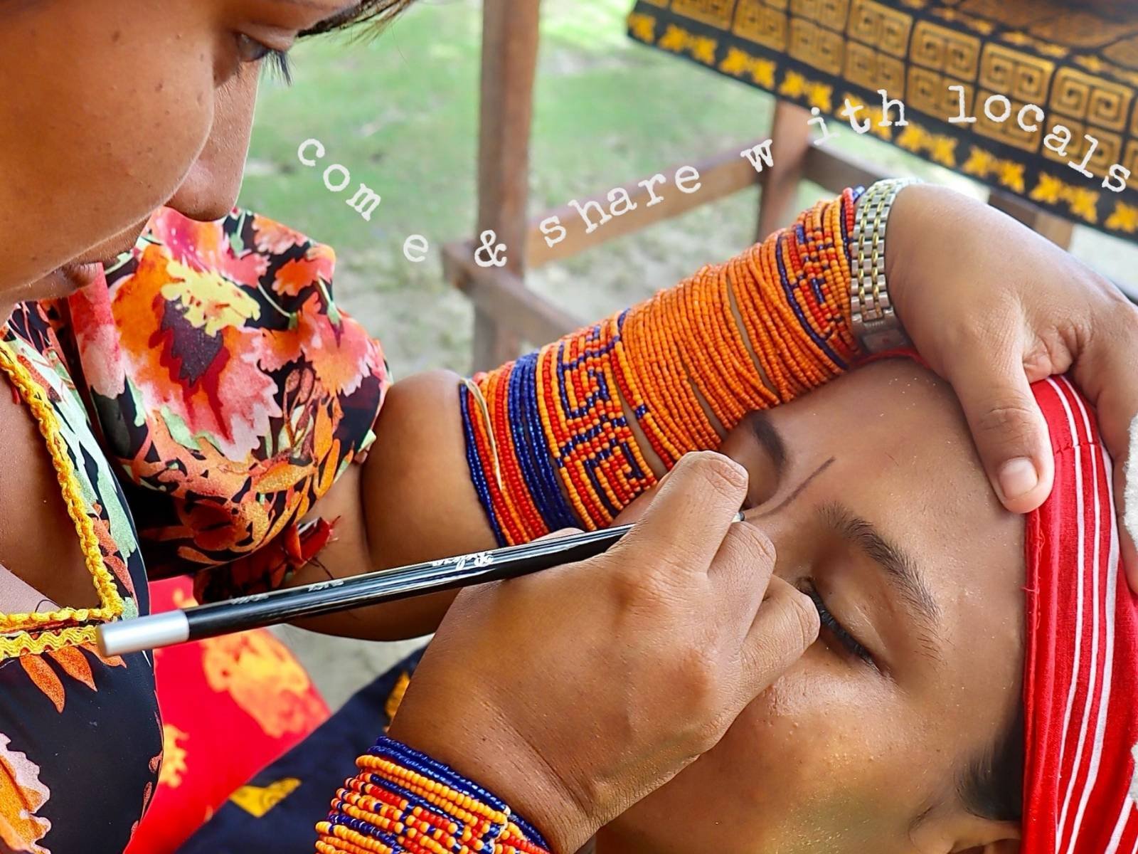 Guna woman painting traditional mola art on tourist during cultural visit in San Blas Panama