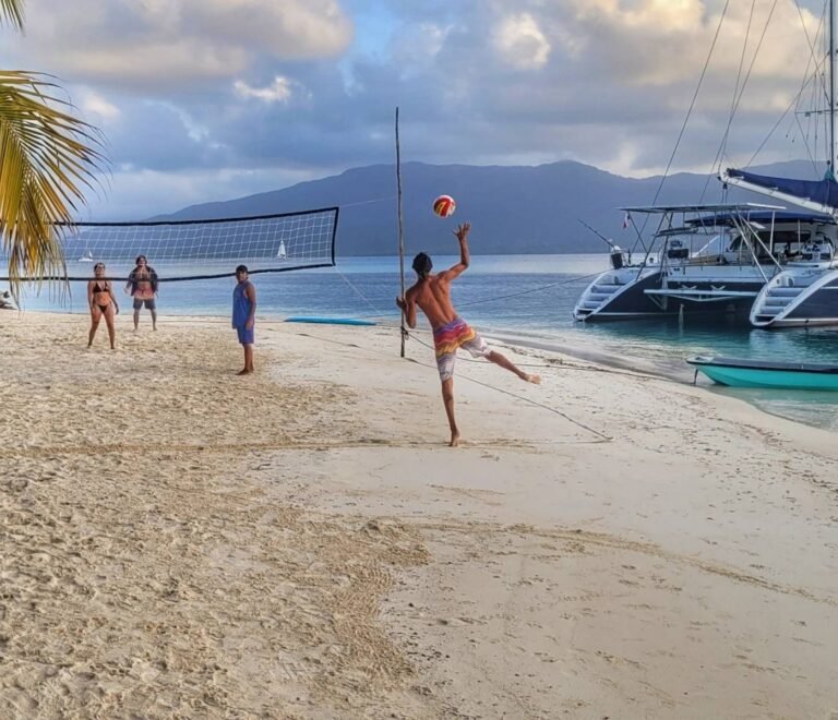 Beach volleyball near Lagoon 57 catamaran anchored on island beach in San Blas