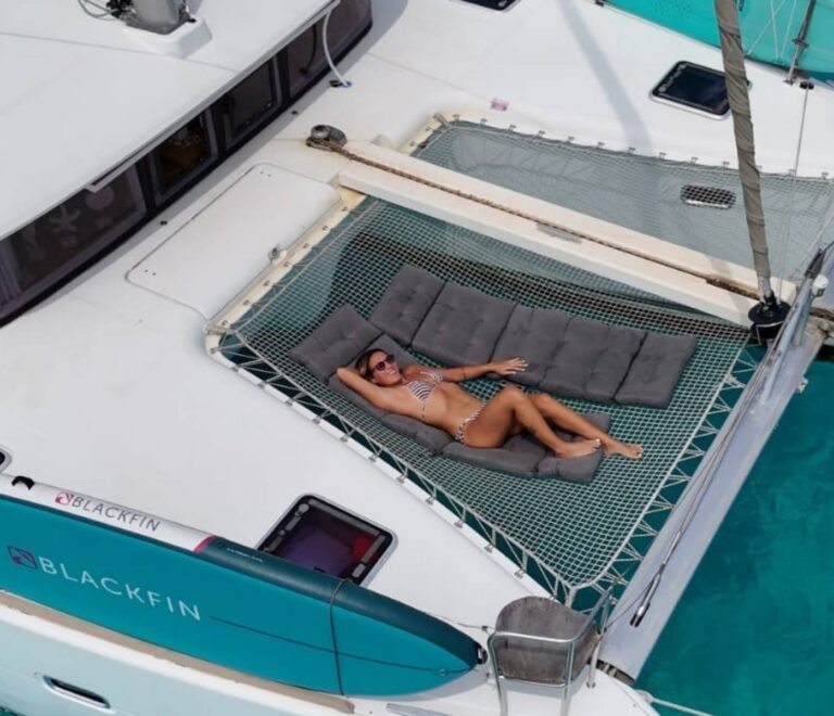 Guest relaxing on front net lounge of Lagoon 40 catamaran in San Blas