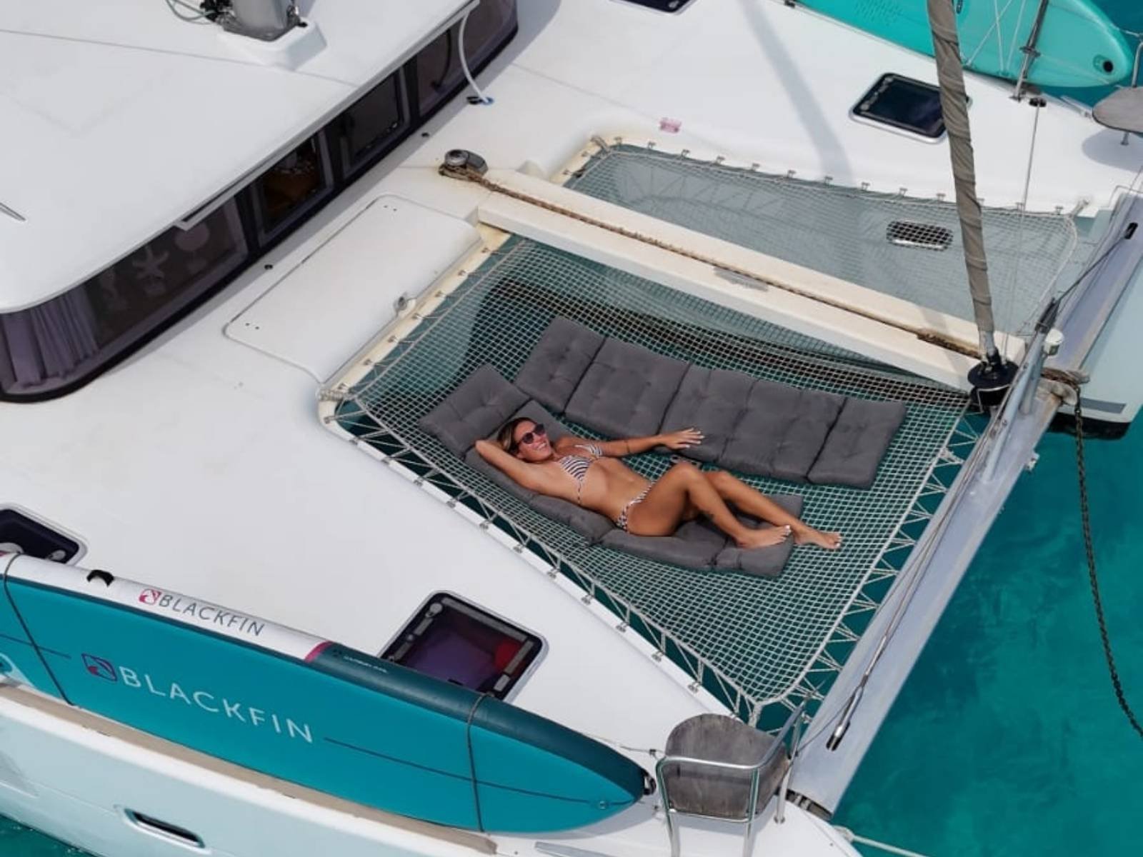 Guest relaxing on front net lounge of Lagoon 40 catamaran in San Blas