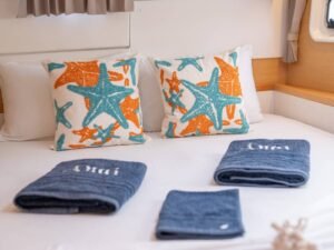 detalle de cama en catamaran Lagoon 40 en San Blas con almohadas decoradas y toallas organizadas