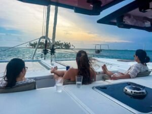 Guests relaxing on front nets of Lagoon 56 catamaran at sunset in San Blas