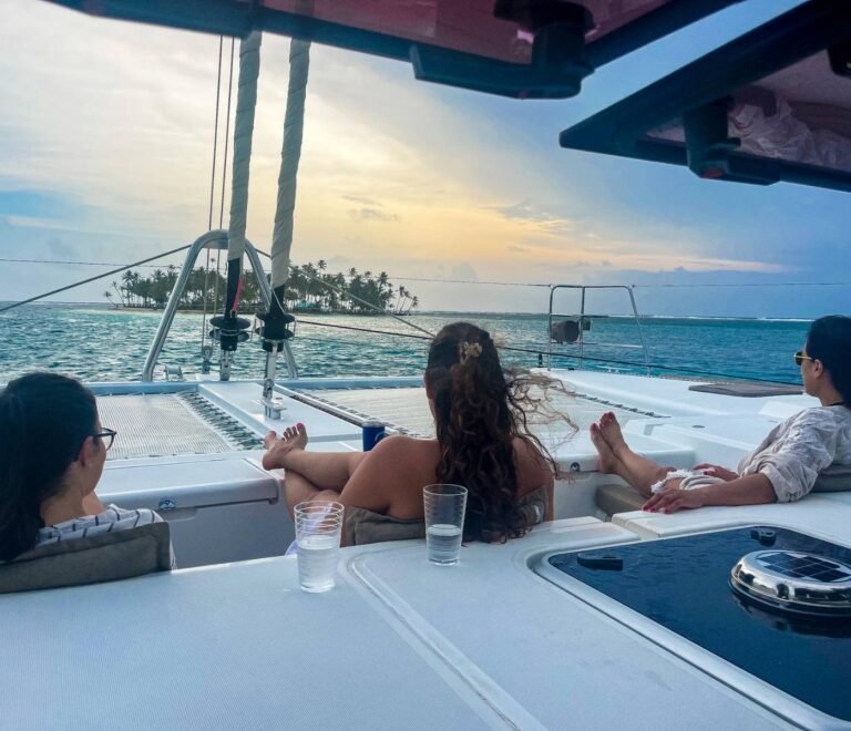 Guests relaxing on front nets of Lagoon 56 catamaran at sunset in San Blas