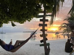 Persona descansando en hamaca al atardecer en San Blas Panamá con vista al mar Caribe y palmeras