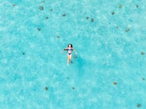 Guest floating in crystal clear waters of Dutch Cays San Blas aerial view