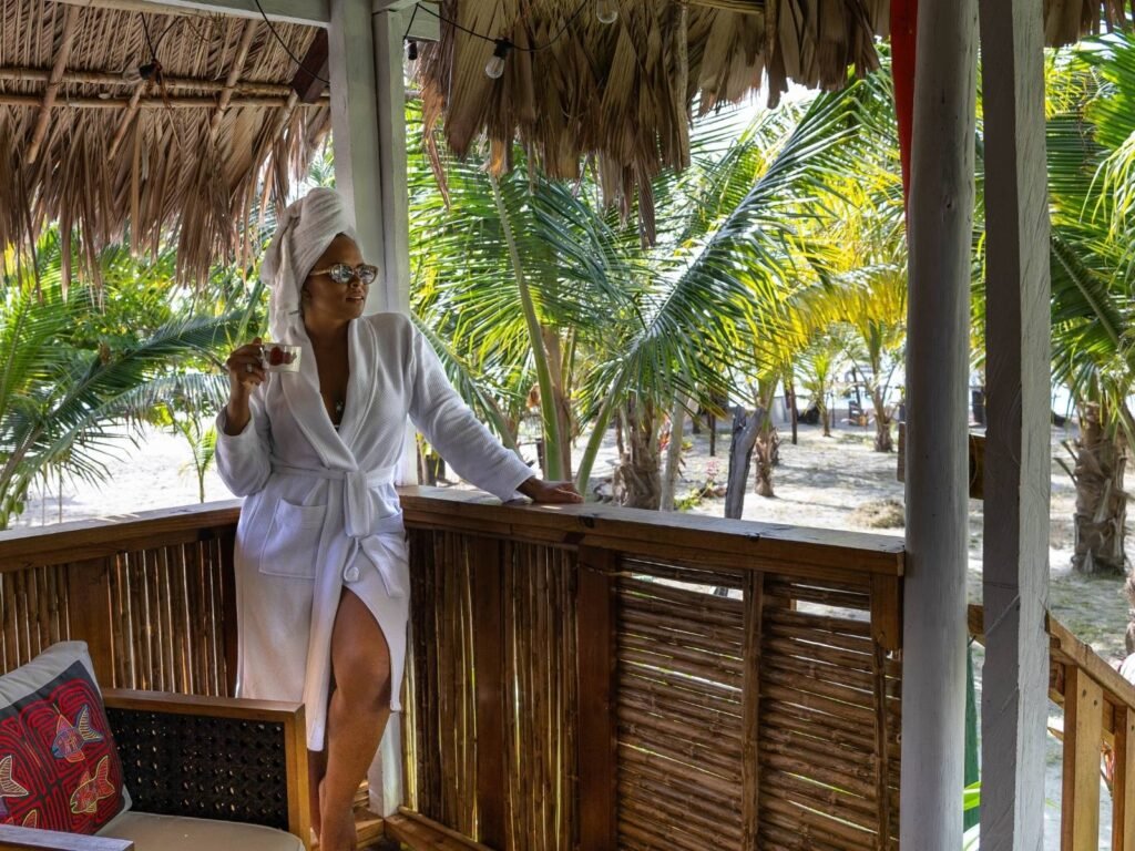 Persona relajándose en terraza de cabaña en Cayos Holandeses San Blas con bebida y vista tropical