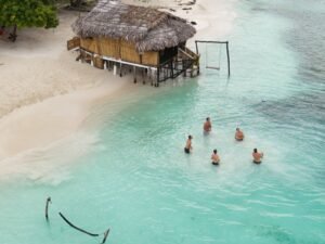 Guests swimming in turquoise waters near bungalow in Dutch Cays San Blas