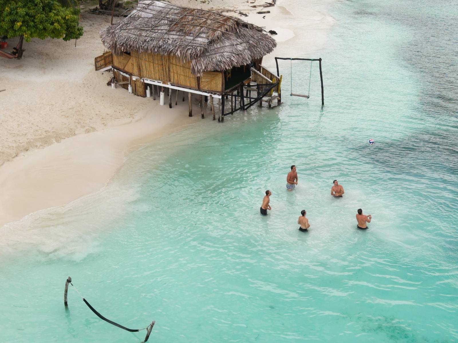 Guests swimming in turquoise waters near bungalow in Dutch Cays San Blas